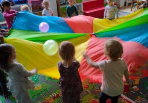 Dzieci bawią się chustą animacyjną odbijając na niej dwa balony
